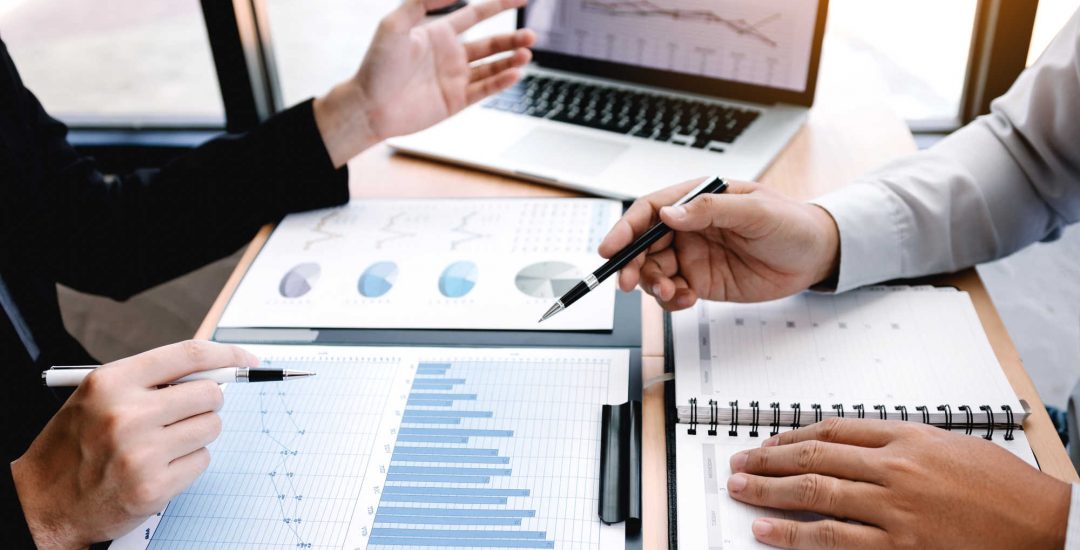 Male manager is explaining about the company's cost graph on the laptop computer for employees to listen to and share the analysis together.